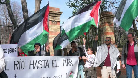 A-group-of-protestors-hold-a-banner-and-wave-flags-during-a-march-in-solidarity-for-Palestine