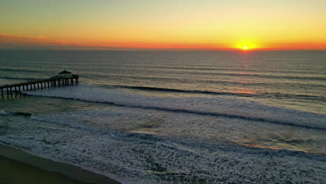 Aerial-view-of-sunset-at-the-beach,-pier-observatory-point-towards-stunning-calm-ocean