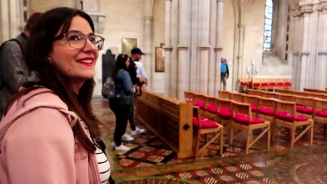 Slow-motion-capture-of-a-smiling-woman-with-glasses-inside-Christ-Church,-with-other-visitors-in-soft-focus