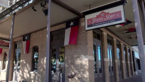 Texas-Star-store-in-Abilene,-Texas-with-Texas-state-flags-moving-on-a-windy-day-and-stable-video-shot