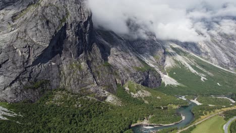 Aerial-footage-showing-the-Rauma-river-in-Norway,-with-mountains,-greenery-and-grass