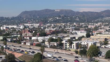 East-Hollywood-over-101-Freeway-traffic,-neighborhood-and-famous-sign-during-day,-aerial-view