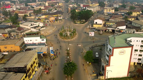 Aerial-view-tilting-away-from-the-Tamzou-Roundabout,-sunset-in-Ebolowa,-Cameroon