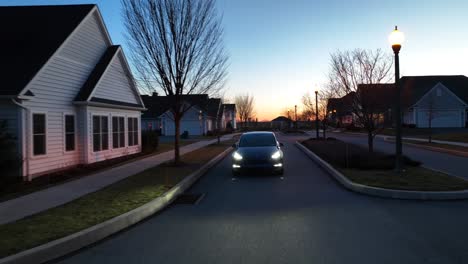 Tesla-driving-in-modern-American-neighborhood-at-dusk