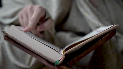 Close-Up-Of-Finger-Reading-And-Tracing-Lines-From-Religious-Book,-symbolizing-the-pursuit-of-home-based-studying-and-learning