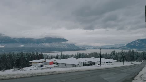 High-Vantage-Point-View-of-Houses-in-the-Winter-With-Mountains-and-Lake-and-Trees