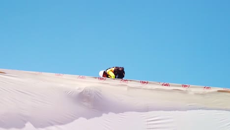 Gimbal-shot-of-a-construction-worker-on-the-roof-of-a-pre-fab-house-at-a-modular-building-site-in-West-Los-Angeles,-California