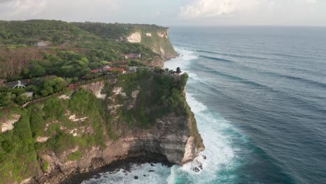 Drone-view-of-famous-Balinese-Hindu-temple-in-Uluwatu-with-cliffs-and-ocean-waves,-Bali,-Indonesia