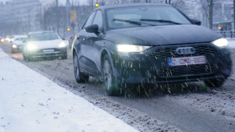 Vehículos-Que-Circulan-Por-Una-Carretera-Bulliciosa-En-Medio-De-La-Nieve-Que-Cae-En-Bruselas,-Bélgica---Plano-Medio