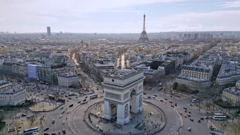 Triumphal-arch-or-Arc-de-Triomphe-with-Tour-Eiffel,-Montparnasse-tower-and-La-Defense-skyscrapers-in-background,-Paris-cityscape,-France
