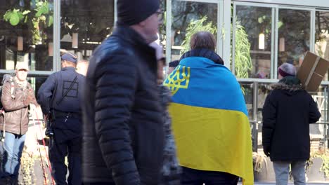 Mann-In-Ukrainische-Flagge-Gehüllt-Und-Polizei,-Protest-Gegen-Den-Russischen-Krieg