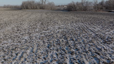 Suelo-Labrado-Congelado-De-Una-Tierra-De-Cultivo-Con-Escasa-Capa-De-Nieve,-Antena