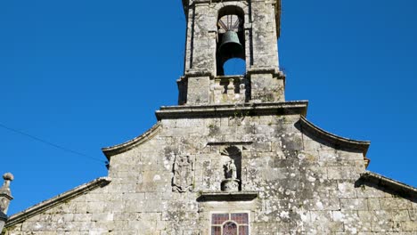 Tilt-up-establish-of-entracne-to-San-Xoan-de-Rio-church-and-bell-tower-against-blue-sky