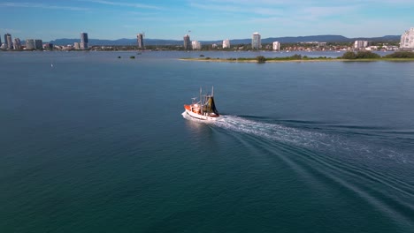 Circular-aerial-views-over-the-Broadwater-as-a-fishing-trawler-comes-in-to-dock-on-the-Gold-Coast,-Australia