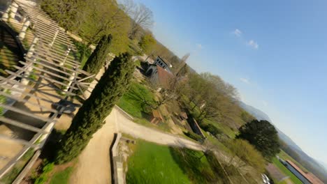Racing-drone-flying-over-gardens-and-fountains-of-Villa-Arnaga,-Cambo-les-Bains-in-Pyrenees-Atlantiques,-New-Aquitaine-in-France