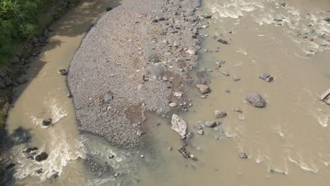 Ein-Mann-Trägt-Flusssteine-In-Einer-Schwimmenden-Wanne-Und-Durchquert-Die-Strömung-Des-Flusses