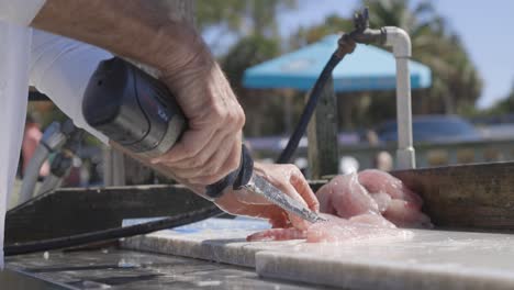 Man-filleting-red-snapper-fish-with-electric-saw-at-bait-shop-in-Sarasota-Florida