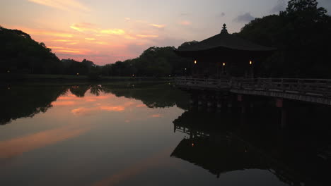 Durante-La-Puesta-De-Sol,-Contempla-El-Cautivador-Recinto-Del-Templo-Toda-ji,-Donde-Los-Vibrantes-Tonos-Naranjas-Se-Reflejan-En-El-Agua,-Acentuando-El-Encanto-Del-Pequeño-Templo-En-Nara,-Japón.