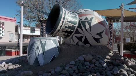 Close-up-of-a-pottery-sculpture-with-water-pouring-out-and-pan-to-mural-in-downtown-Deming,-New-Mexico