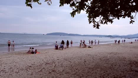 Touristen-Und-Einheimische-Treffen-Sich-Am-Strand-Von-Aonang,-Krabi,-Thailand,-Und-Genießen-Die-Sonne,-Den-Sand-Und-Die-Lebendige-Atmosphäre-Des-Türkisfarbenen-Wassers,-Bevor-Die-Sonne-Untergeht