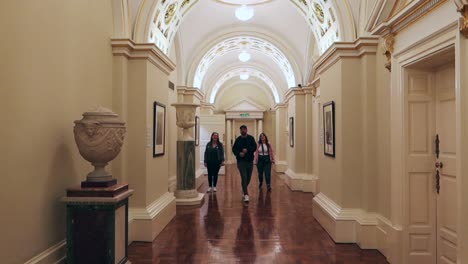 Visitors-stroll-through-an-ornate-Dublin-Castle-corridor-admiring-its-classical-architecture