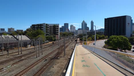 Radweg-Hinunter-Rampe-Neben-Bahngleis-An-Claisebrook-Station-Perth,-Mit-Der-Stadt-Im-Hintergrund