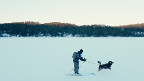 Un-Hombre-Esquía-Junto-A-Su-Perro-En-Un-Paisaje-Nevado---Toma-De-Seguimiento