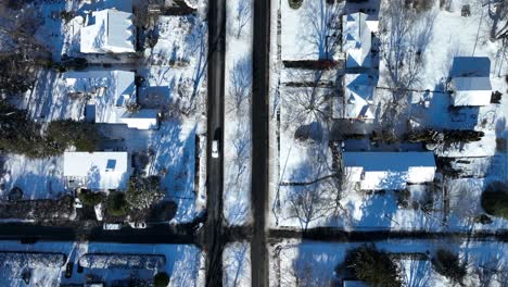 Aerial-Birds-Eye-shot-of-white-car-driving-on-road-in-snowy-american-town