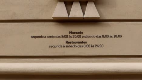 Opening-hours-printed-on-the-facade-of-Bolhao-Market-building,-Porto