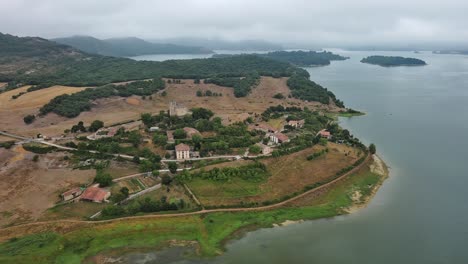 Nanclares-de-gamboa-village,-lush-greenery-by-the-lake,-cloudy-day,-basque-country,-spain,-aerial-view