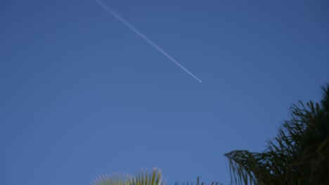Airplane-leaves-contrail-wake-in-the-blue-sky-above-Cannes-France,-Looking-up-shot