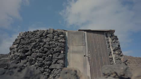 Toma-De-Plataforma-Rodante-De-Una-Casa-Cerrada-Construida-Con-Rocas-Volcánicas-En-Una-Isla.