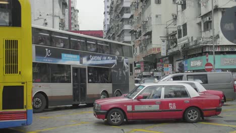 Taxi-cabs-with-traditional-red-color-wait-at-an-intersection-with-traffic---slow-motion