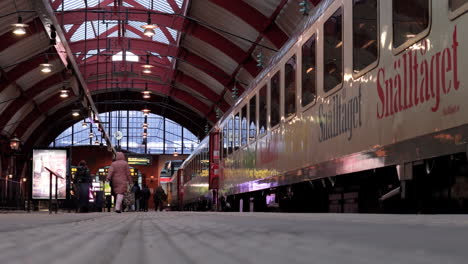 Travelers-hastily-walk-on-platform-next-to-static-train,-Malmo-Central-Station