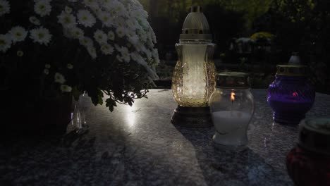 A-grave-illuminated-from-behind-as-a-hand-places-a-candle-on-it,-symbolizing-reverence-and-remembrance-in-a-solemn-moment