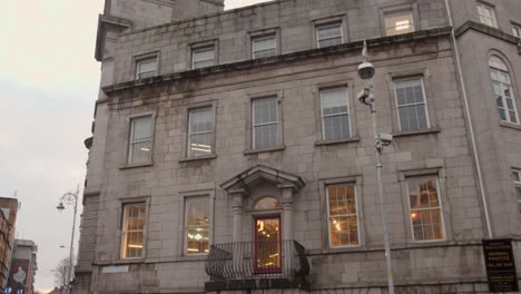 Tilt-shot-of-architecture-of-Mercer's-Medical-Centre-during-daytime-beside-a-busy-road-in-Dublin,-Ireland