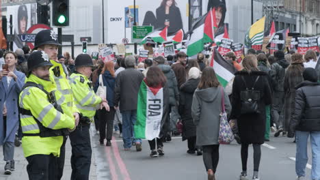 Three-Police-Officers-Oversee-Peaceful-Protestors-in-London-Carrying-Palestine-Flags-and-Banners