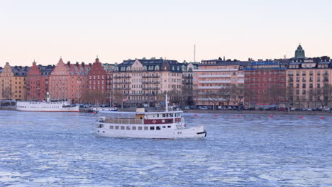Ferry-cruising-through-icy-waters-of-Lake-Mälaren,-Kungsholmen-skyline