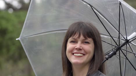 Portrait-of-the-happy,-smiley-brunette-woman-under-the-transparent-umbrella