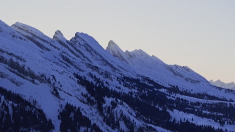 Vista-Aérea-Que-Muestra-La-Silueta-De-Una-Cadena-Montañosa-Nevada-Al-Amanecer