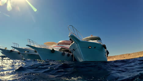 View-from-water-of-boats-anchored-near-blue-sea-shore-in-Sharm-El-Sheikh,-Egypt