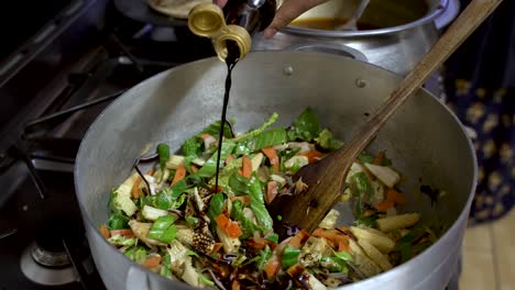 Gemüse-Im-Wok-Anbraten-Und-Soße-Darüber-Gießen,-Kücheneinstellung,-Lebendige-Farben