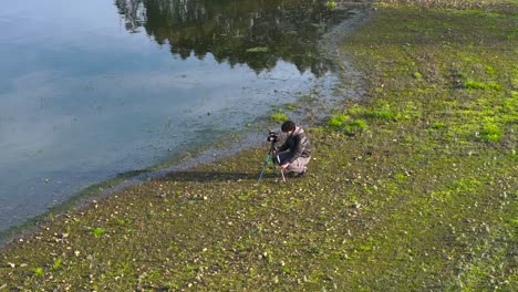 Fotógrafo-De-Naturaleza-Con-Cámara-Sobre-Trípode-En-La-Orilla-Del-Lago.