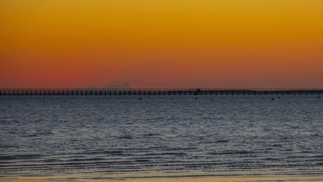 Eine-Goldene-Sonne,-Die-Hinter-Einem-Riesigen-Pier-Im-Meer-Aufgeht