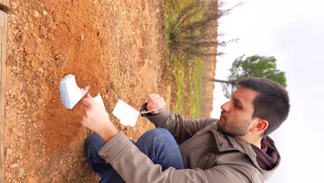 Hombre-Enterrando-Material-Biodegradable-Con-Semillas-En-Un-Parque.