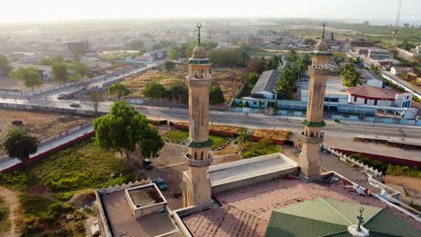 Aerial-orbit-view-of-the-minarets-of-King-Fahad-mosque-and-Banjul-cityscape-at-sunset,-Gambia---West-Africa