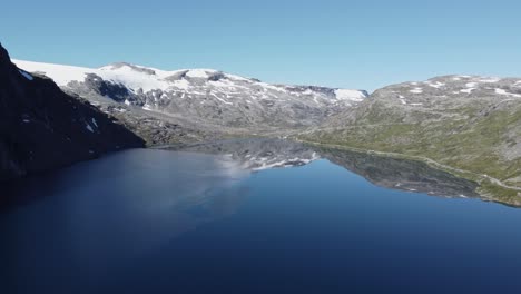 Lake-in-the-Rauma-Commune-of-Norway,-with-snow-capped-mountains-in-the-background