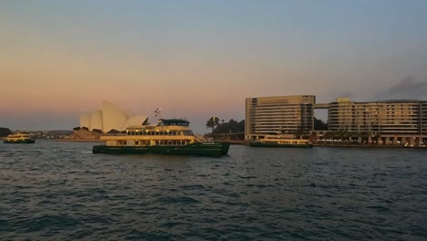 Vista-Del-Atardecer-Del-Puerto-De-Sydney-Con-Ferries-Cerca-De-La-ópera,-Cálido-Resplandor-En-El-Agua