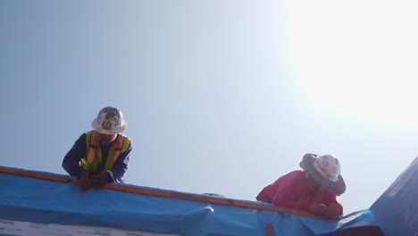 Gimbal-booming-down-shot-of-a-construction-crew-working-on-the-siding-of-a-pre-fab-modular-unit-at-a-building-site-in-West-Los-Angeles,-California