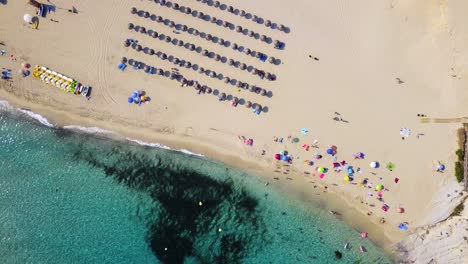 Cala-mesquida-beach-with-colorful-umbrellas-and-clear-blue-waters,-aerial-view,-on-the-island-of-Mallorca,-Spain,-in-the-Mediterranean-Sea